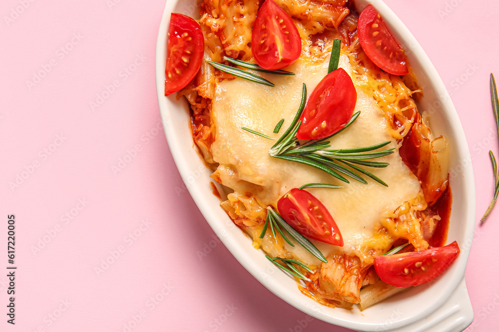 Baking dish of pasta with tomato sauce and cheese on pink background