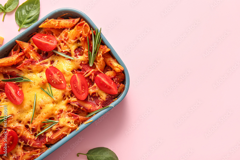 Baking dish of pasta with tomato sauce and cheese on pink background