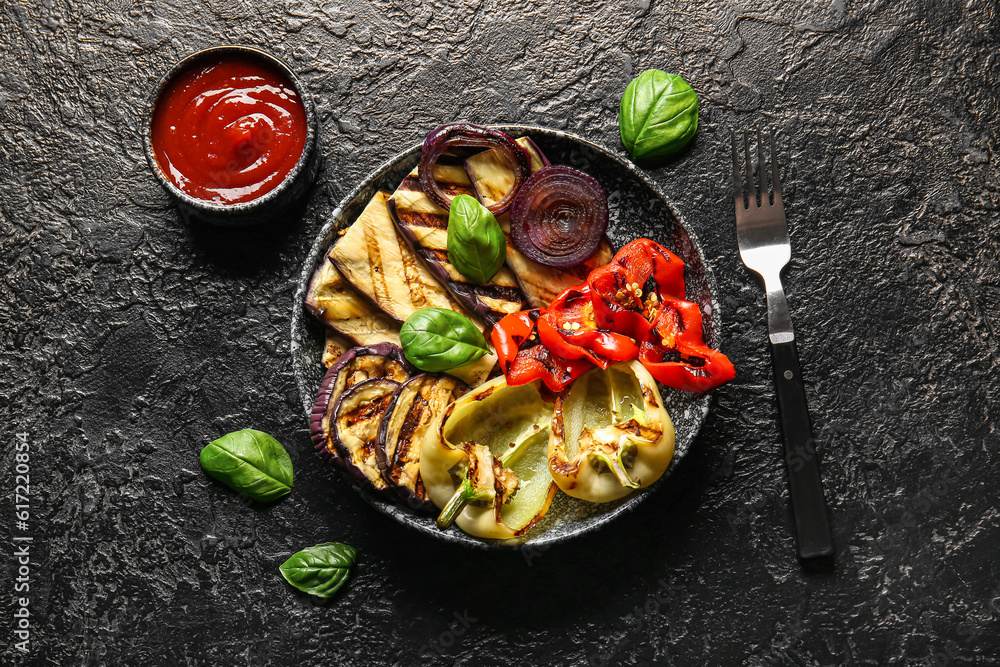 Plate with tasty grilled vegetables and sauce on black background