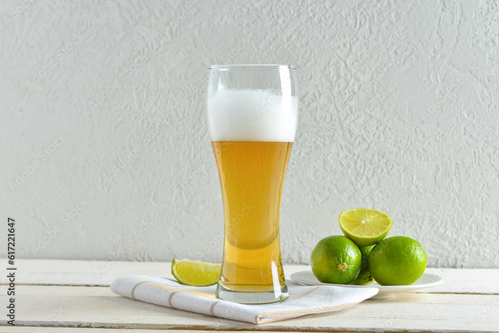 Glass of cold beer with lime on table