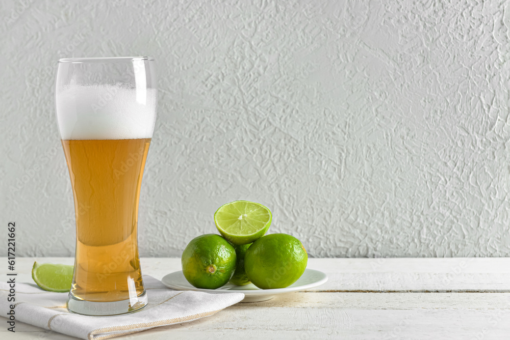 Glass of cold beer with lime on table