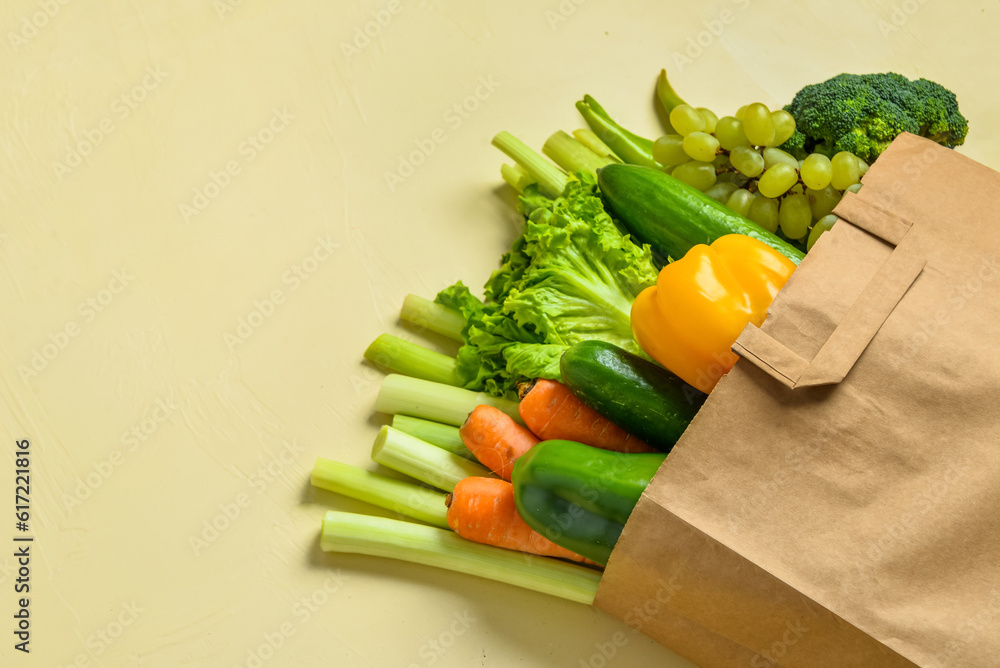 Paper bag with fresh vegetables and fruits on beige background