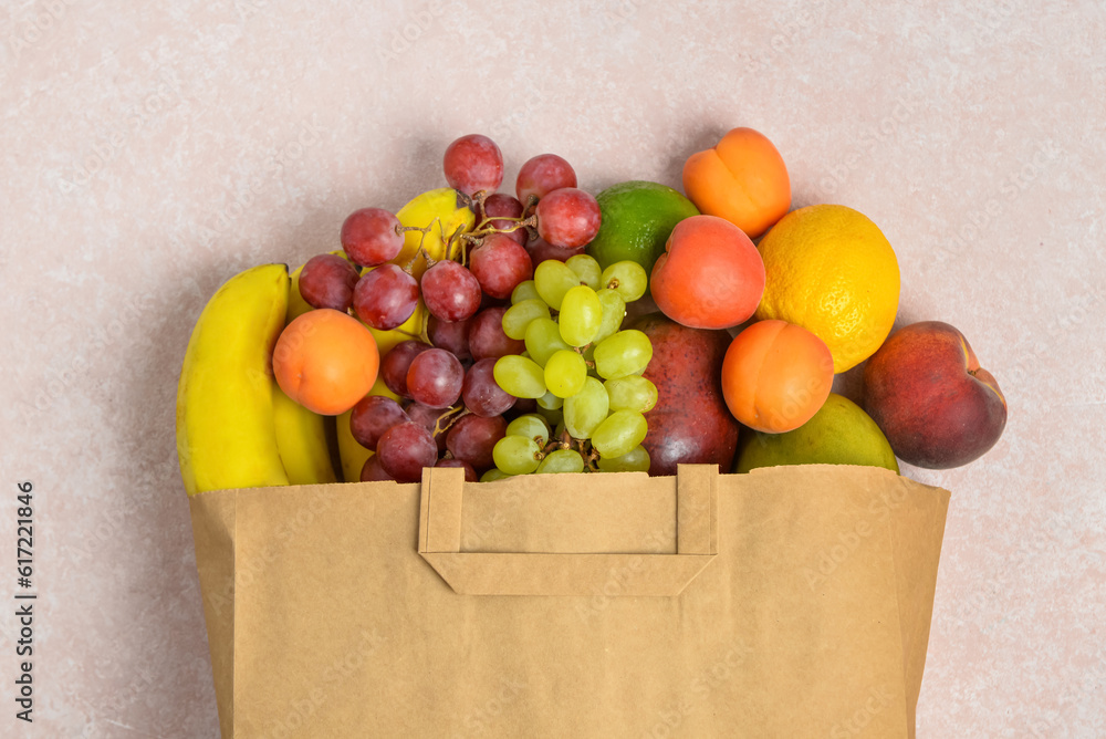 Paper bag with fresh fruits on grey background