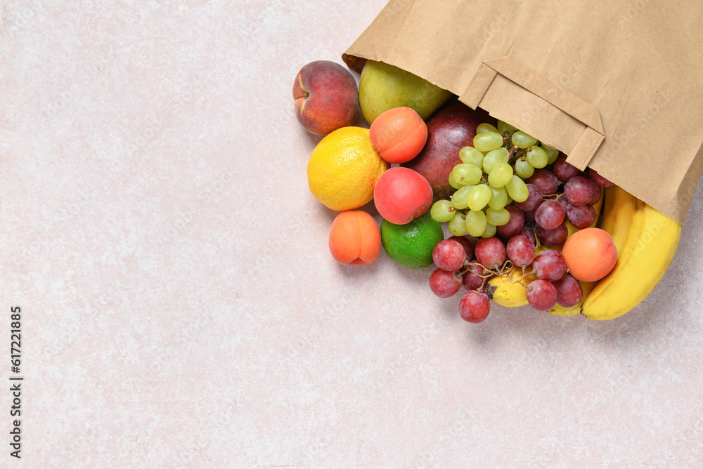 Paper bag with fresh fruits on grey background