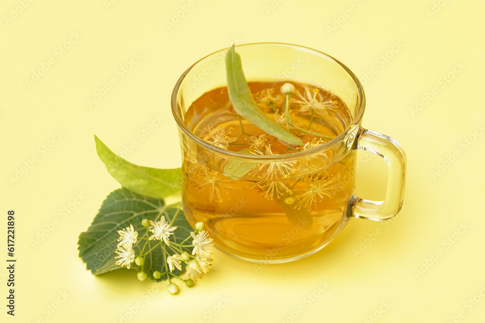 Glass cup of linden tea on yellow background