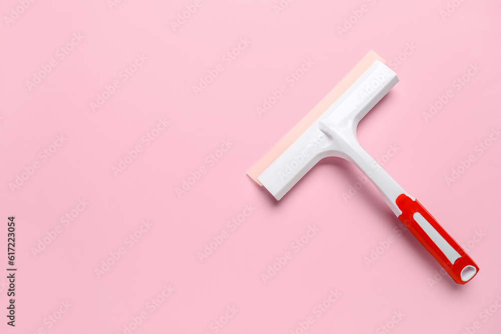 White plastic squeegee on pink background