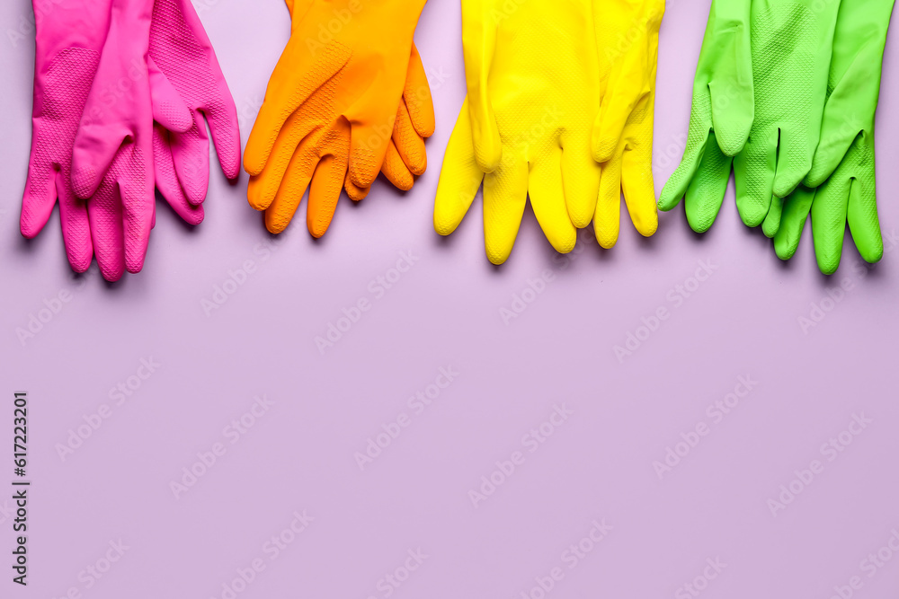 Colorful rubber gloves on lilac background