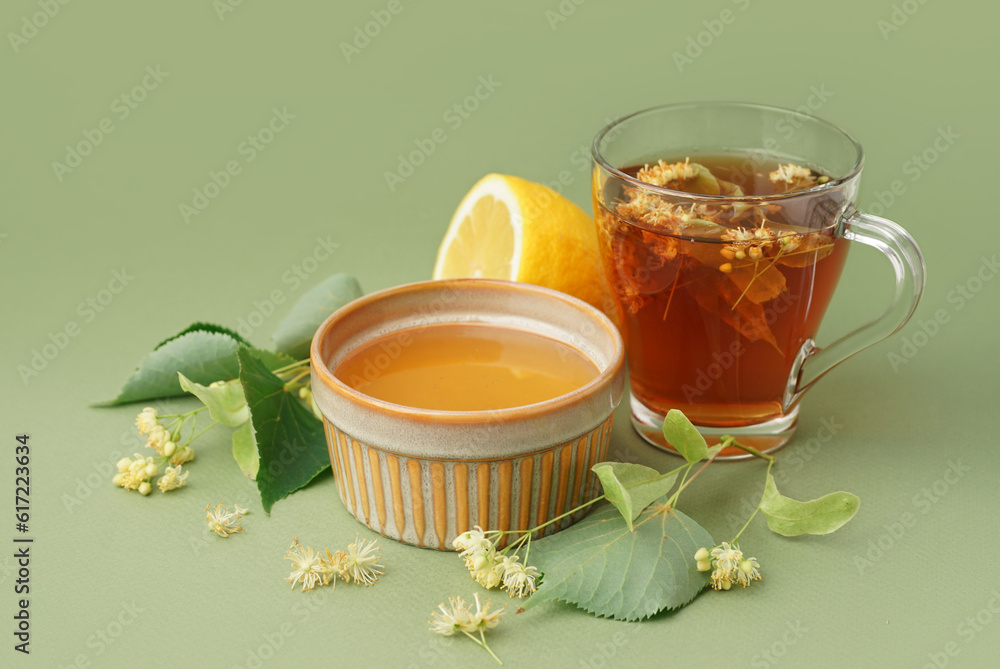 Bowl with linden honey and glass cup of tea on green background