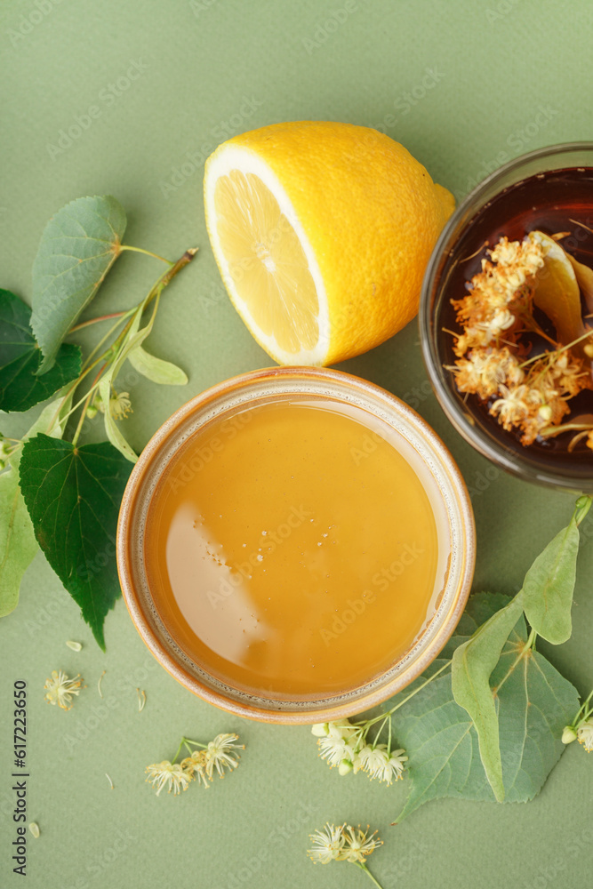 Bowl with linden honey and glass cup of tea on green background