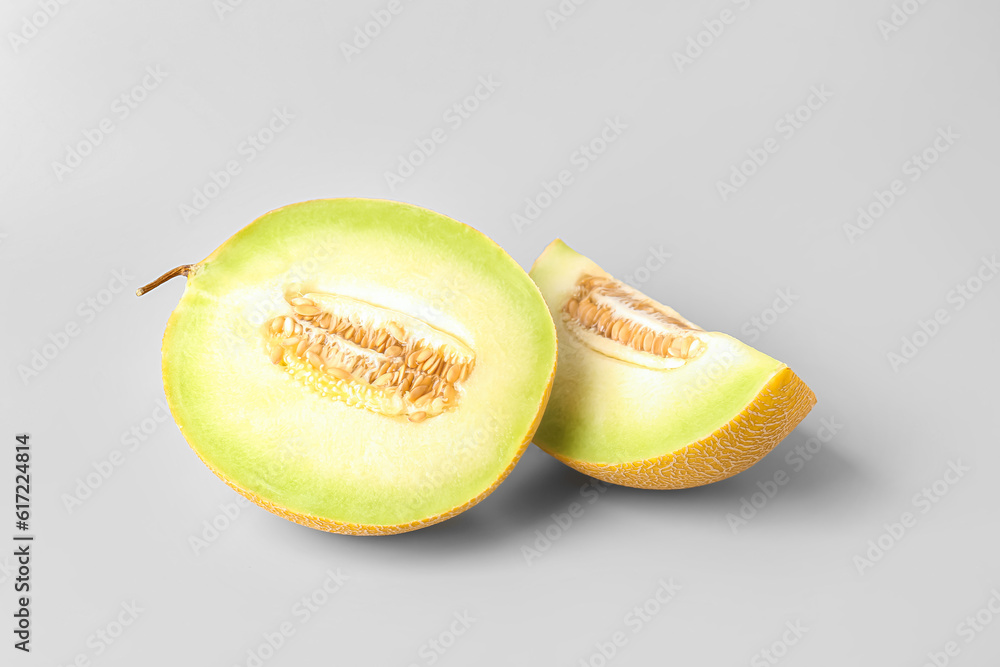 Half of sweet melon with piece on grey background