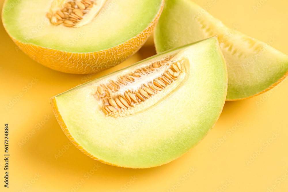 Half of sweet melon with pieces on yellow background