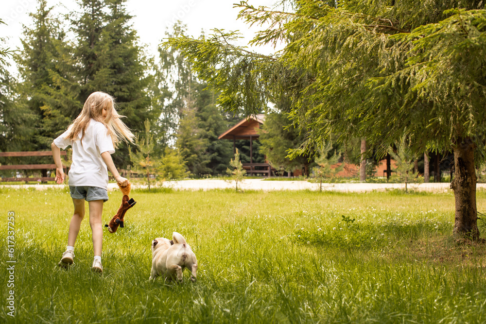 The girl has fun and plays with the dog outdoors. Pug. Pet care. Friendship.