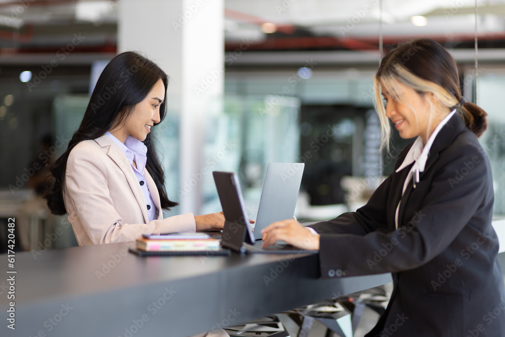 Businesswoman secretary colleague working with laptop in office. Two receptionists work at the count