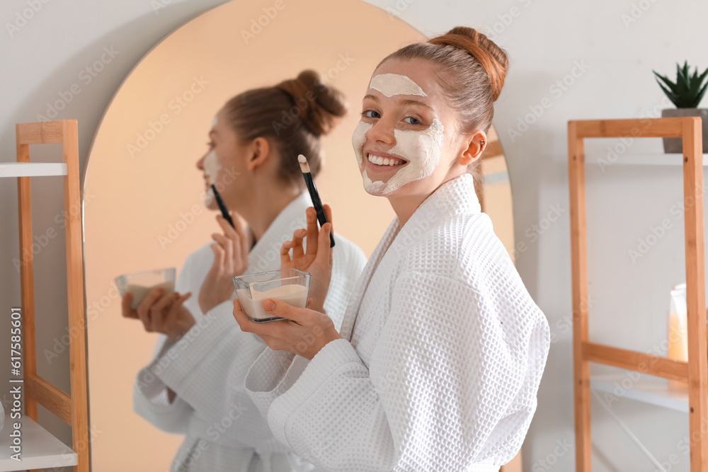 Young woman with turmeric mask and brush in bathroom