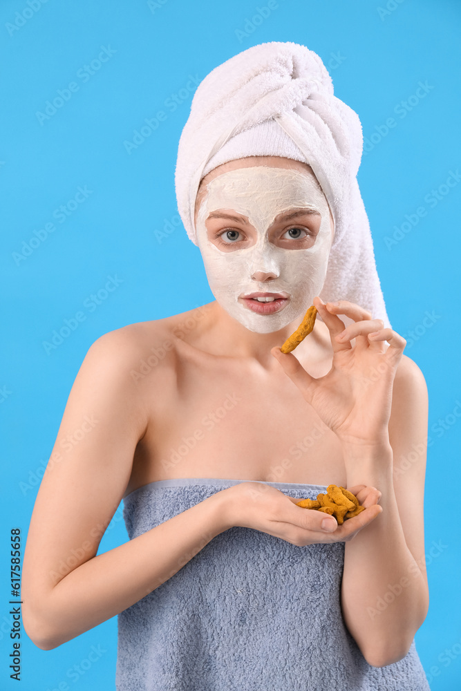 Young woman with applied turmeric mask and roots on blue background