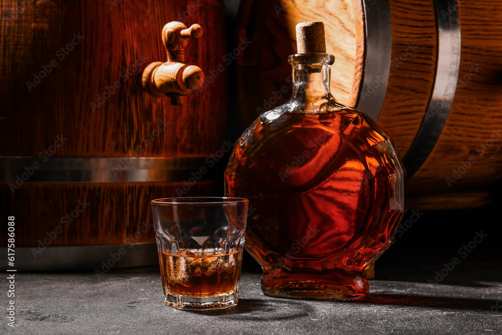 Barrels with bottle and glass of cold rum on wooden table