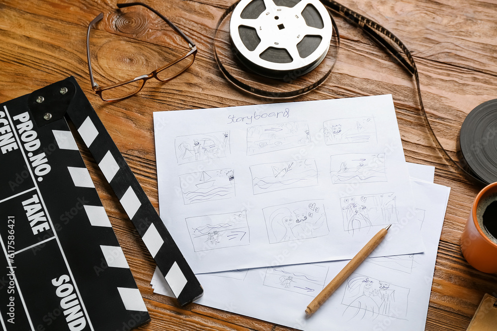 Storyboard with movie clapper and film reel on wooden background