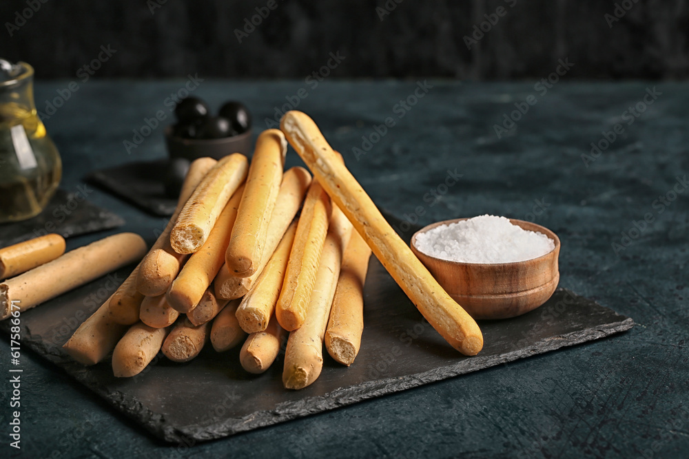 Slate board with tasty Italian Grissini on dark background