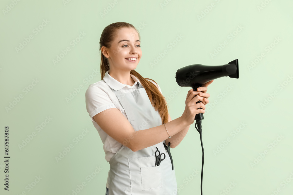 Female hairdresser with dryer on green background