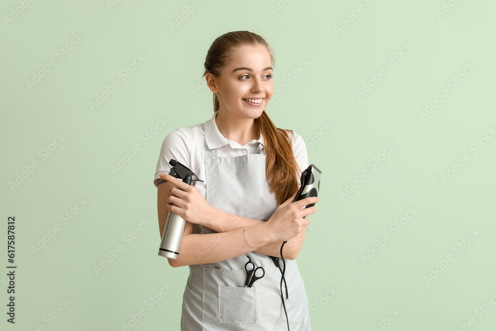 Female hairdresser with trimmer and spray on green background