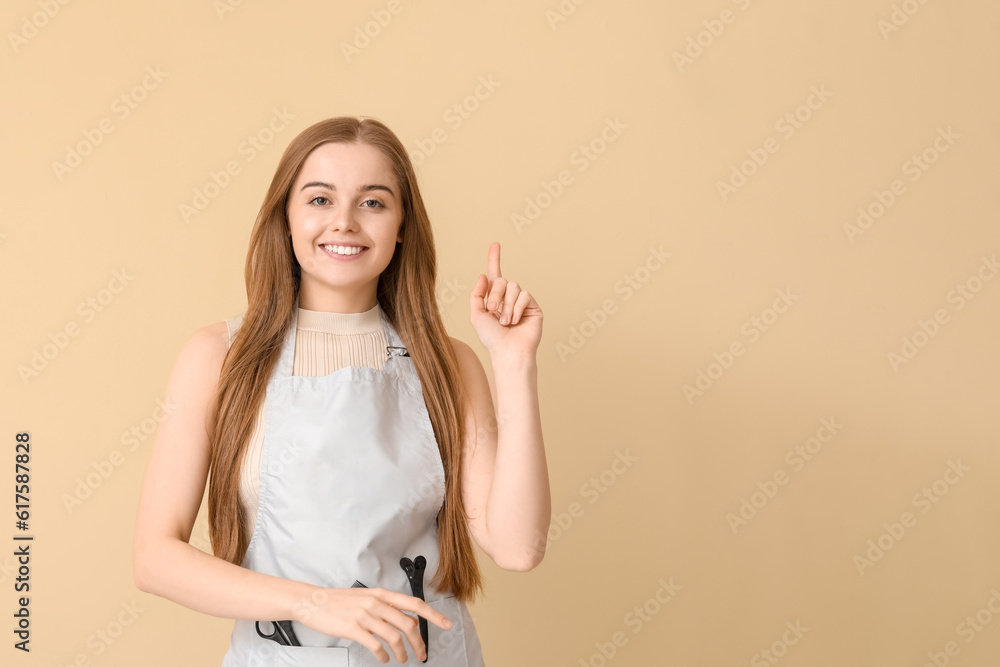 Female hairdresser pointing at something on beige background