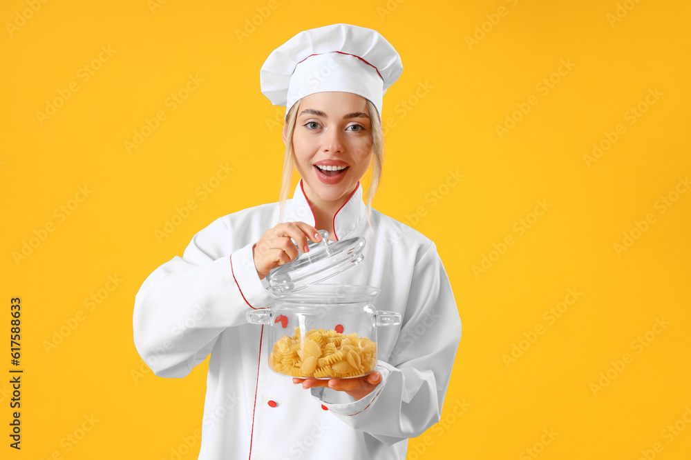 Female chef with cooking pot of pasta on yellow background