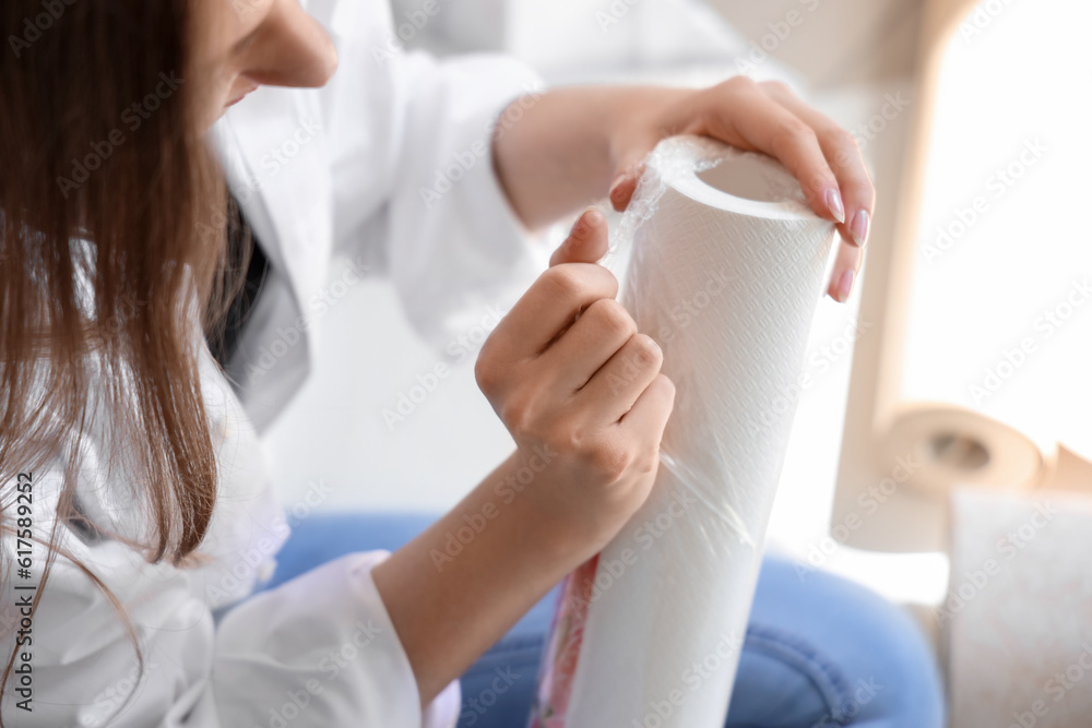 Young woman with wallpaper roll in room