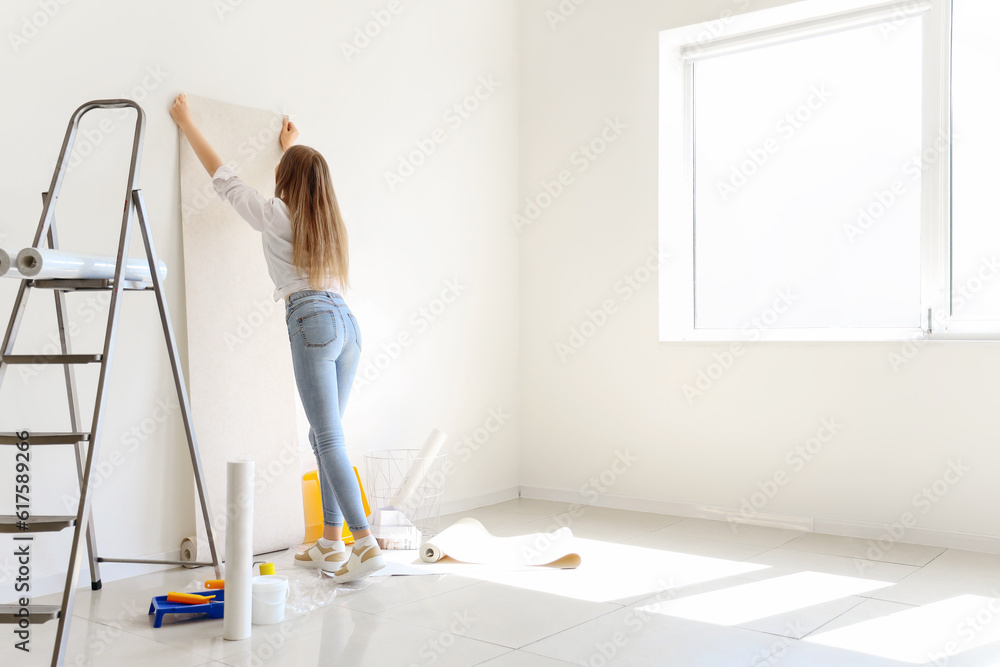 Young woman with wallpaper roll in room