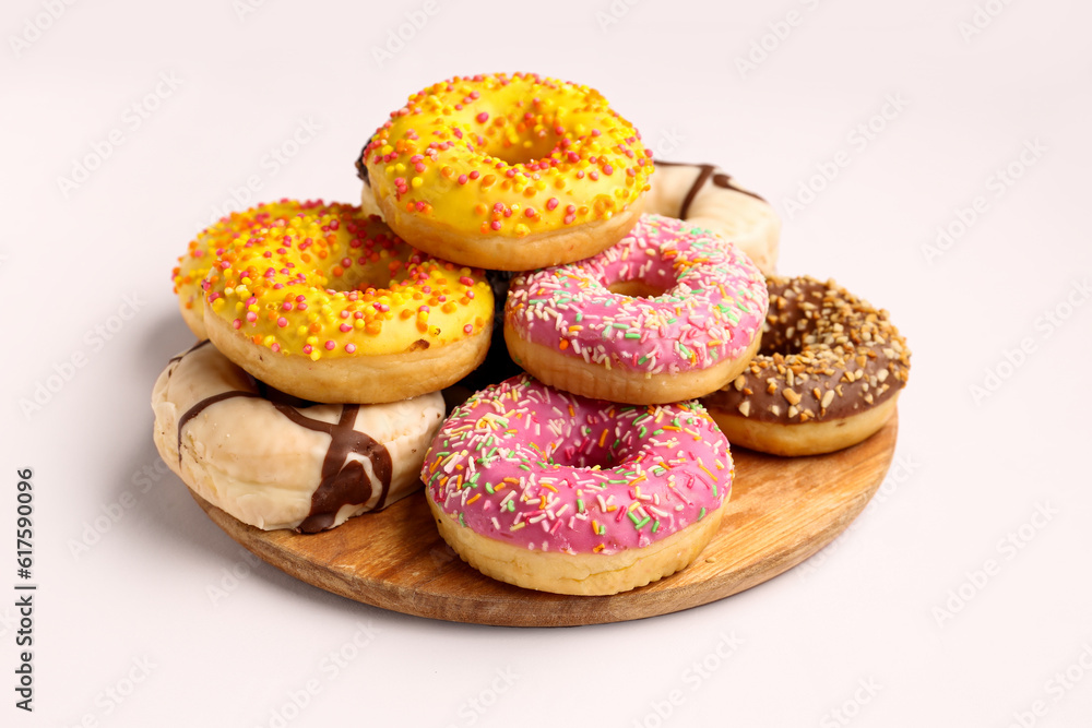 Board with sweet donuts on white background