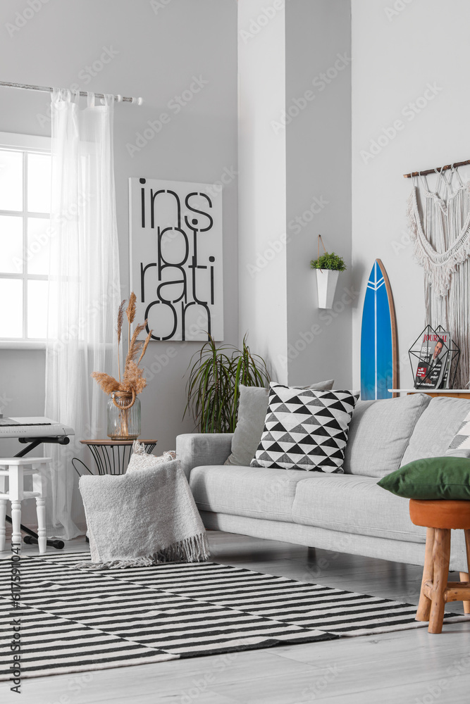 Interior of stylish living room with surfboard, synthesizer and sofa