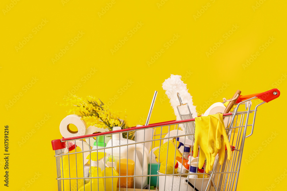 Shopping cart full of cleaning supplies with flowers on yellow background