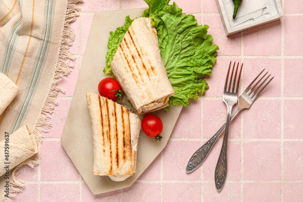 Board of tasty shawarma with lettuce and tomatoes on pink tile table