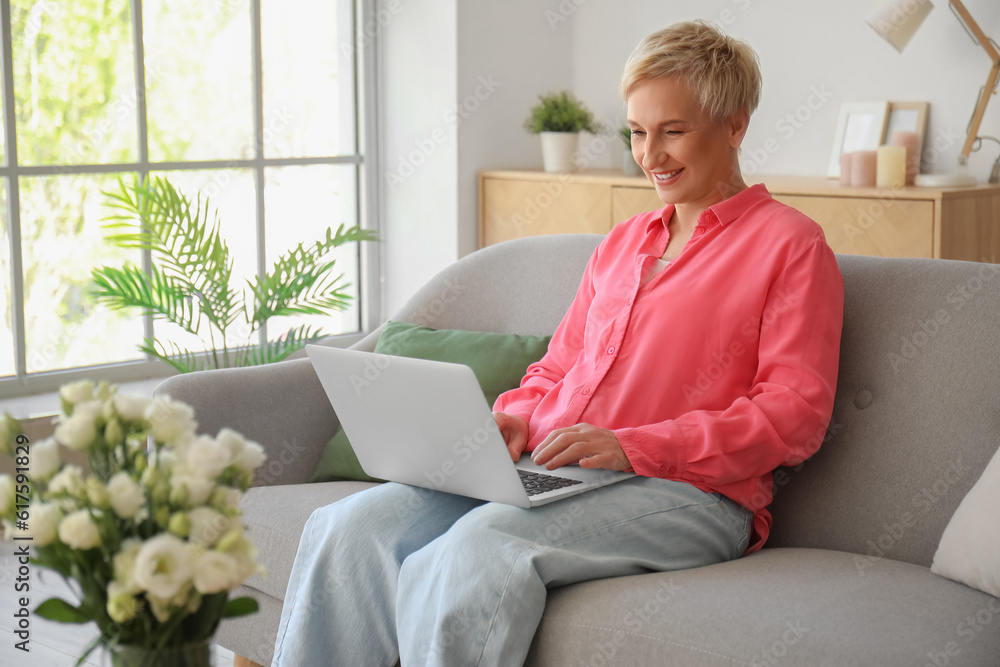 Mature woman using laptop on sofa at home