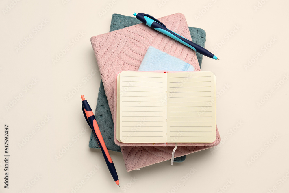 Stack of notebooks and pens on light background