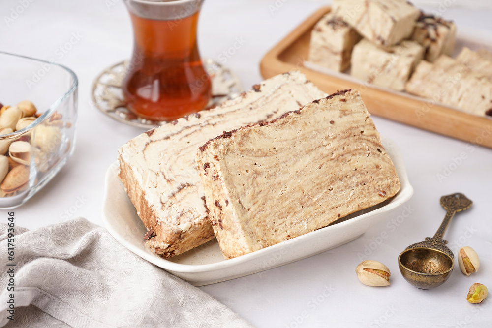 Bowl with pieces of tasty marble halva on light background