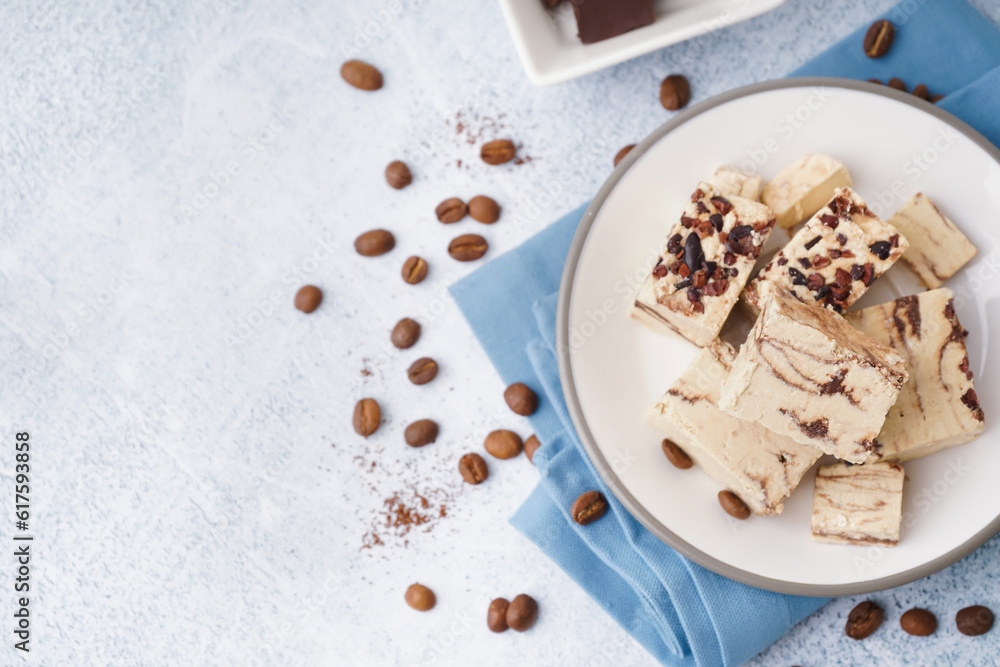 Plate with pieces of tasty marble halva on light background