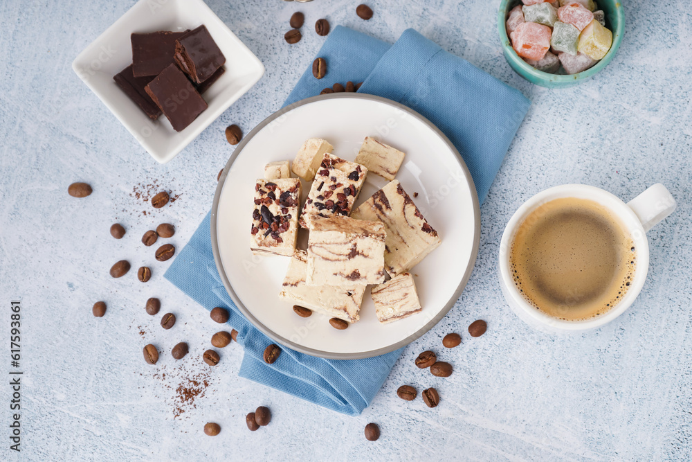 Pieces of tasty marble halva and cup with coffee on light background