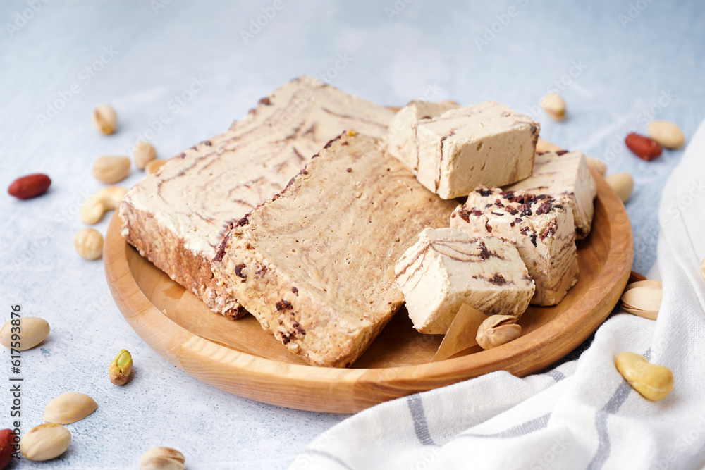 Plate with pieces of tasty marble halva on light background