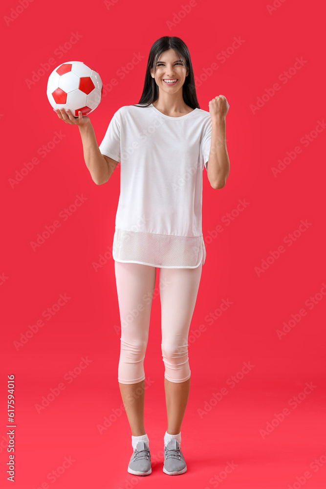 Happy young woman with soccer ball on red background