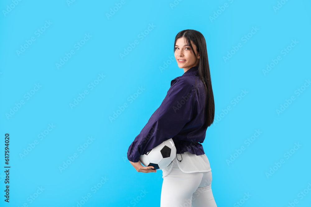 Young woman with soccer ball on blue background