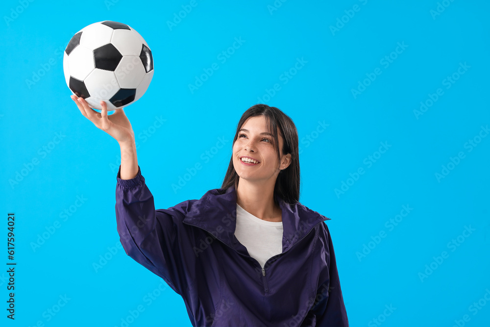 Young woman with soccer ball on blue background