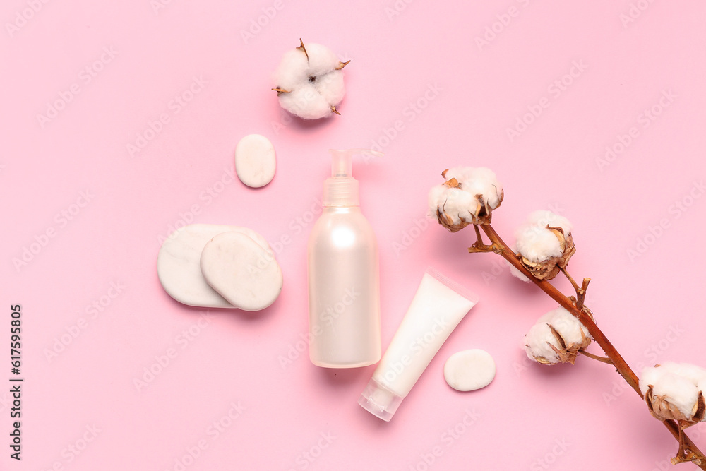 Cosmetic products, spa stones and cotton branch on pink background