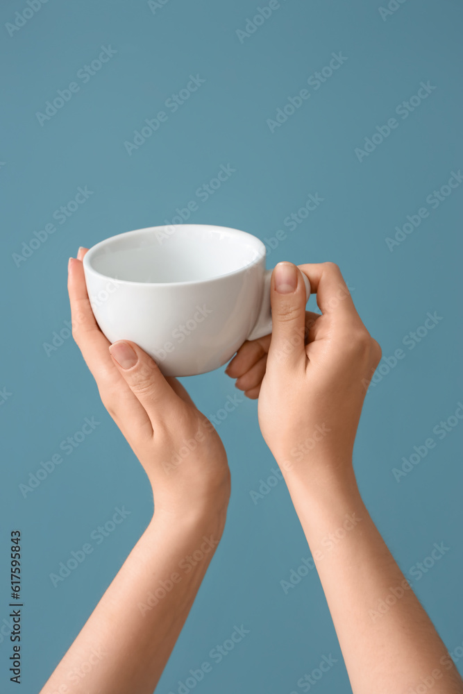 Female hands holding cup on blue background