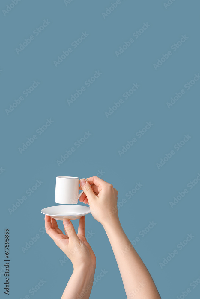 Female hands holding cup and saucer on blue background