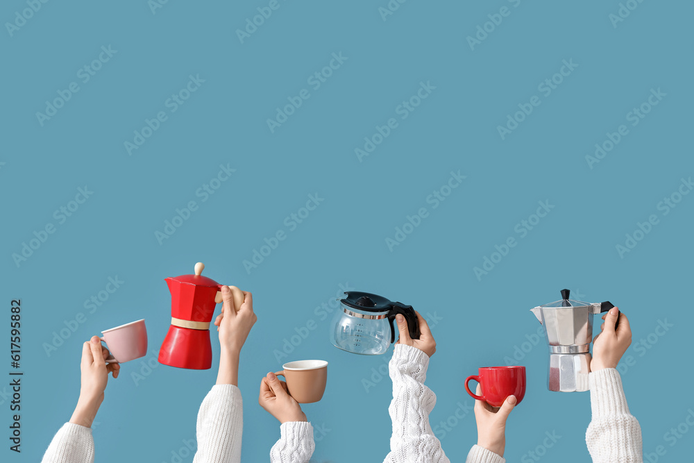 Female hands holding different coffee makers and cups on blue background