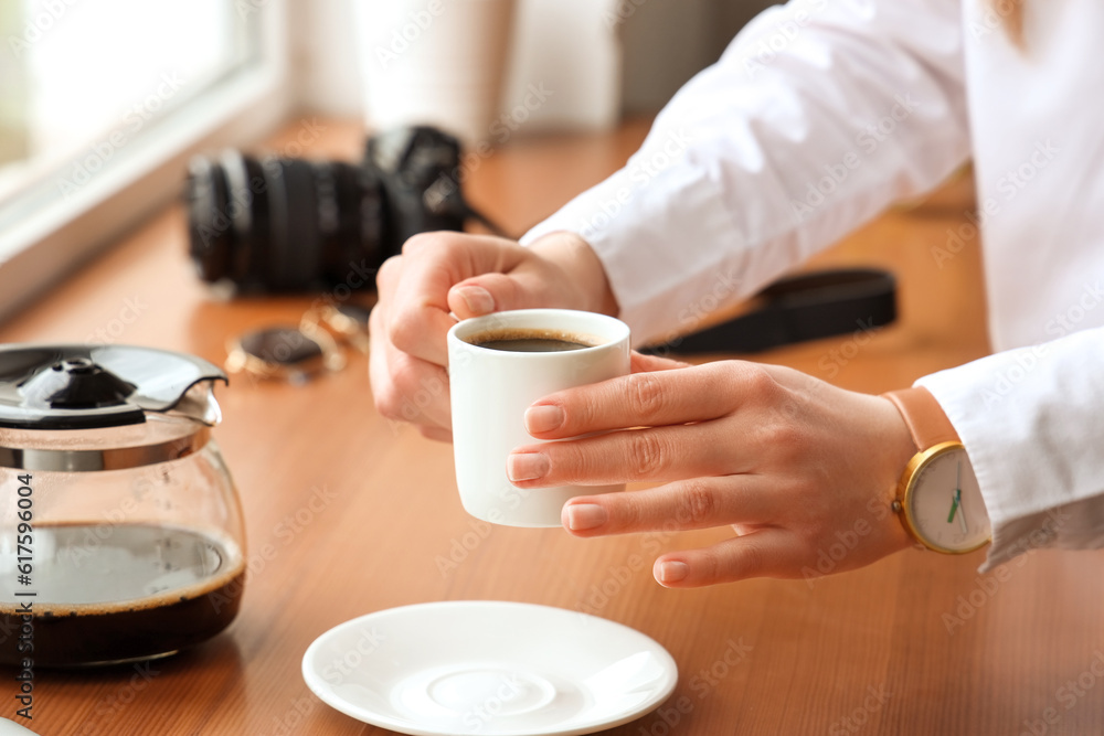 Woman holding cup of delicious coffee on windowsill