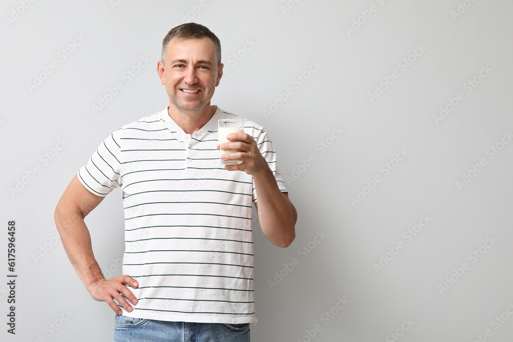 Mature man with glass of milk on white background