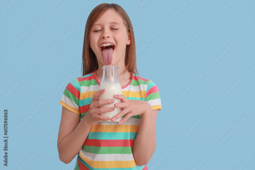 Funny little girl with bottle of milk on light blue background