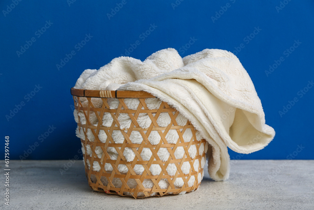 Basket with new soft blanket near blue wall