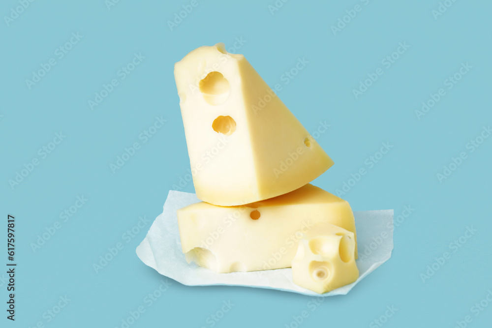 Baking paper with pieces of Swiss cheese on blue background